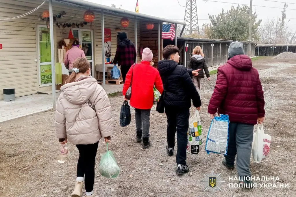 Символічна сцена: стопка мішків з кормом, поліцейський значок на столі і дитячі малюнки