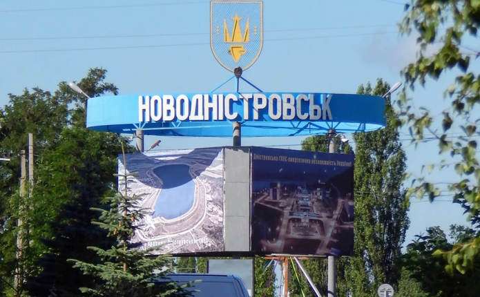 символічна сцена порожньої міської площі ввечері з силуетом сирени, зачиненими крамницями і вантажівкою на тлі хмарного неба