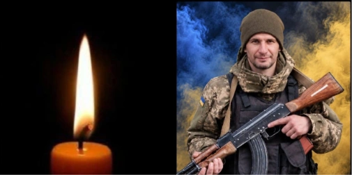символічна сцена: шолом, складений прапор, запалена свічка і квіти на дерев’яному столі