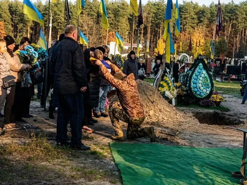 комеморативна сцена: складена військова куртка, шолом і свічка на столі
