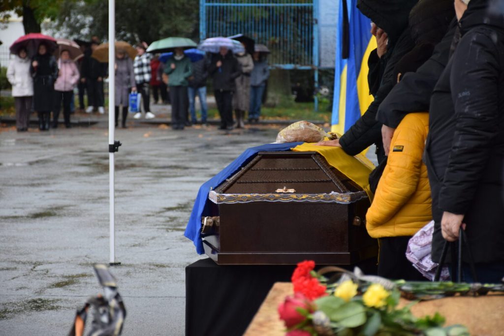 символічна натюрмортна сцена з військовою каскою, складеним прапором, жетоном і свічкою на дерев'яному столі