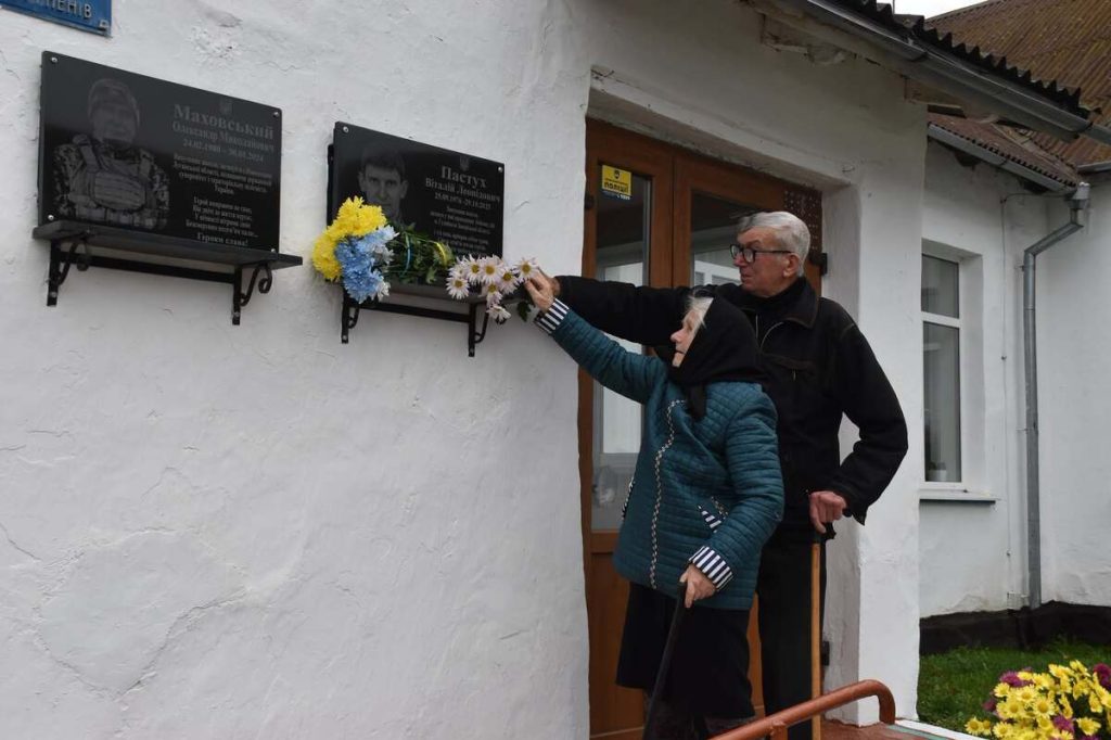 Пам'ятна дошка на шкільній стіні з квітами і свічкою
