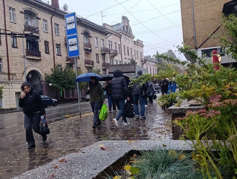 Вовняний шарф, термометр і декоративна сніжинка на дерев'яному столі, символізують похолодання