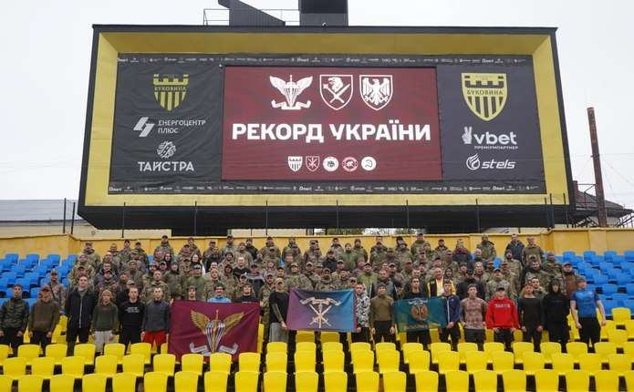 символічна композиція: кросівки, військові жетони і фінішна медаль на траві