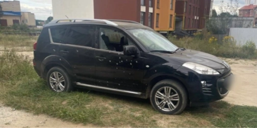 символічна сцена подвірʼя з пошкодженими авто та військовими предметами