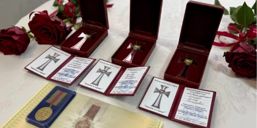 медалі, свічка та складена синьо-жовта стрічка на нейтральному тлі