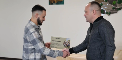 символічна сцена з документами на житло та ключем на дерев’яному столі, складений український прапор на фоні