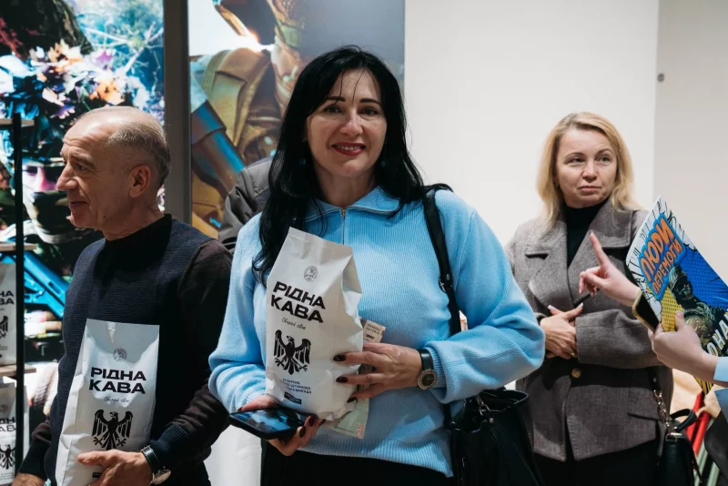 чашка кави поруч із мішком зерен на дерев'яному столі, тепле світло