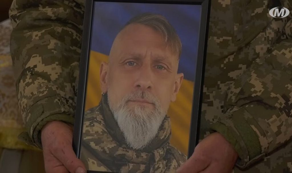 деталь зі складеним військовим шарфом і каскою на дерев'яній лавці, приглушені кольори