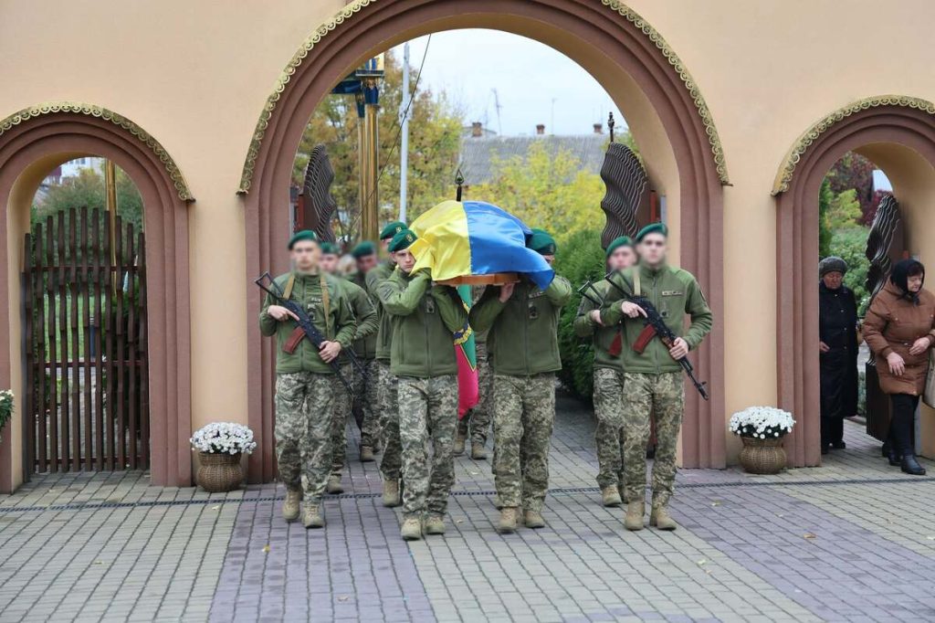 три згорнуті військові кашкети і запалені свічки на дерев'яному столі